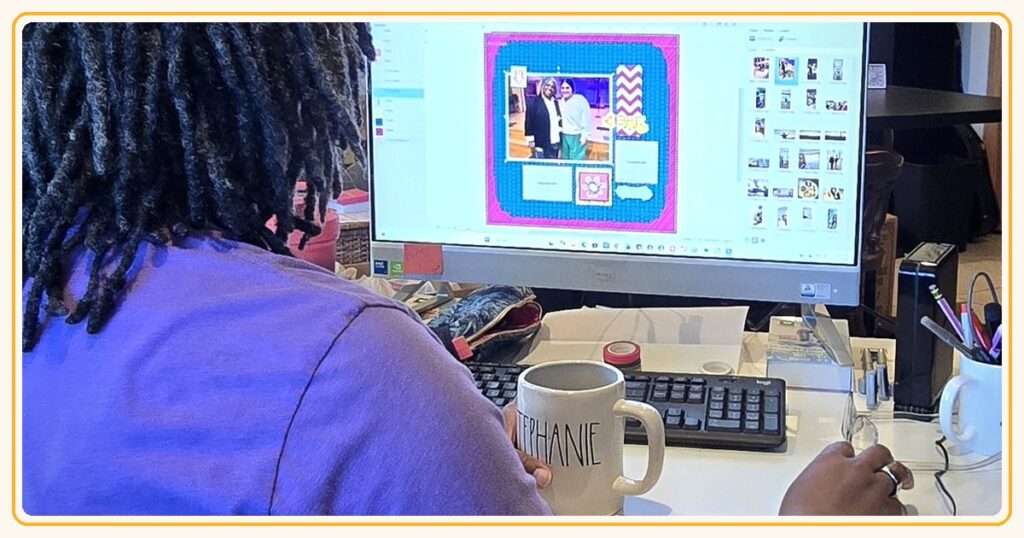 Stephanie at her desk designing a colorful digital scrapbook page in Artisan, with her STEPHANIE coffee mug beside the keyboard